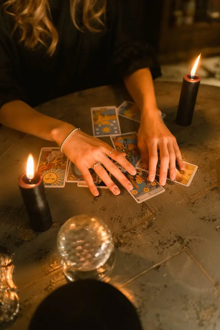 Sobre A woman engaging in a tarot card reading with candles and a crystal ball on a dimly lit table.